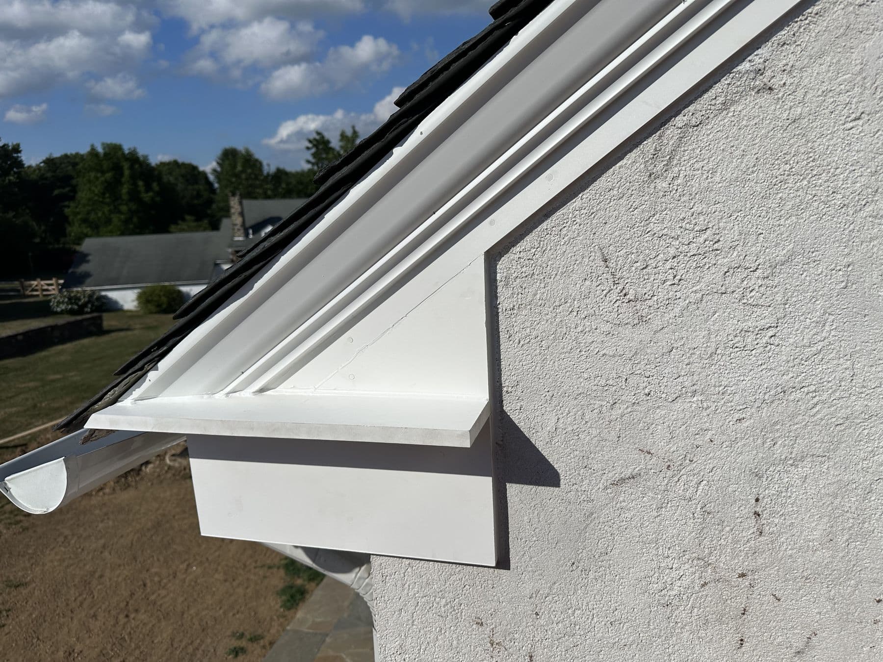 New white PVC rake trim and return on a stucco gable