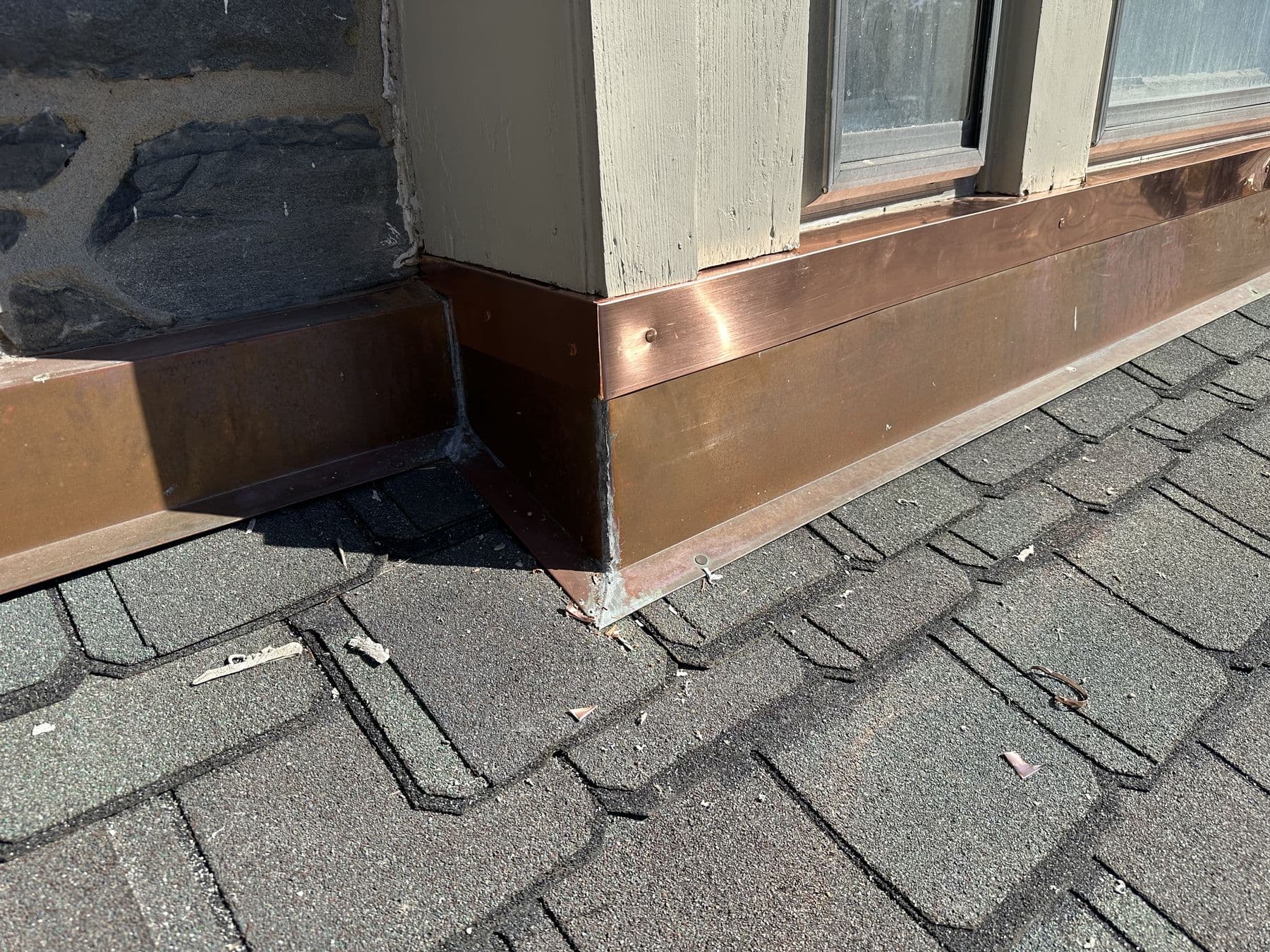 Copper apron flashing under a bay window where it meets the slate roof