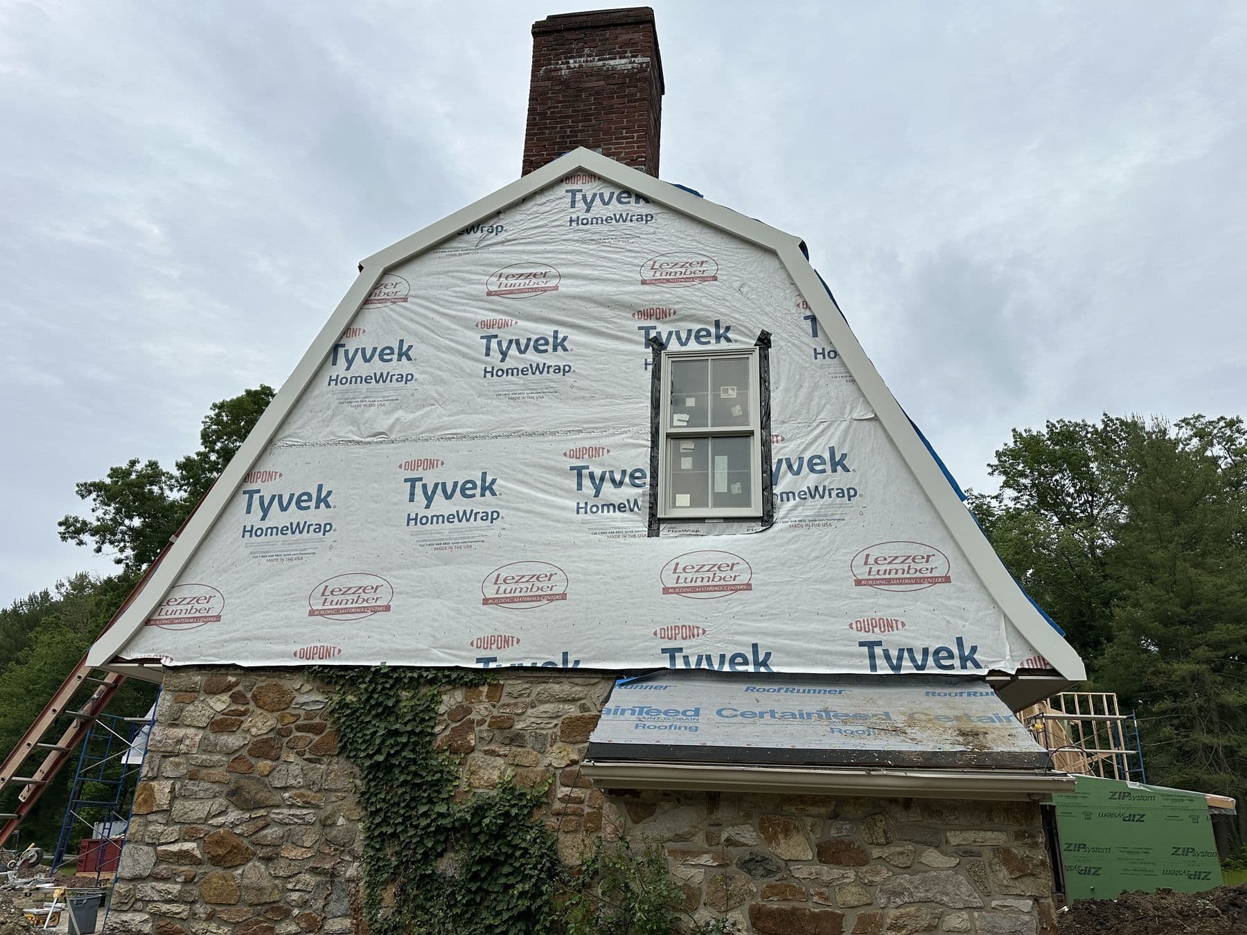 Gambrel gable sheathed and wrapped in Tyvek with a new window opening framed in
