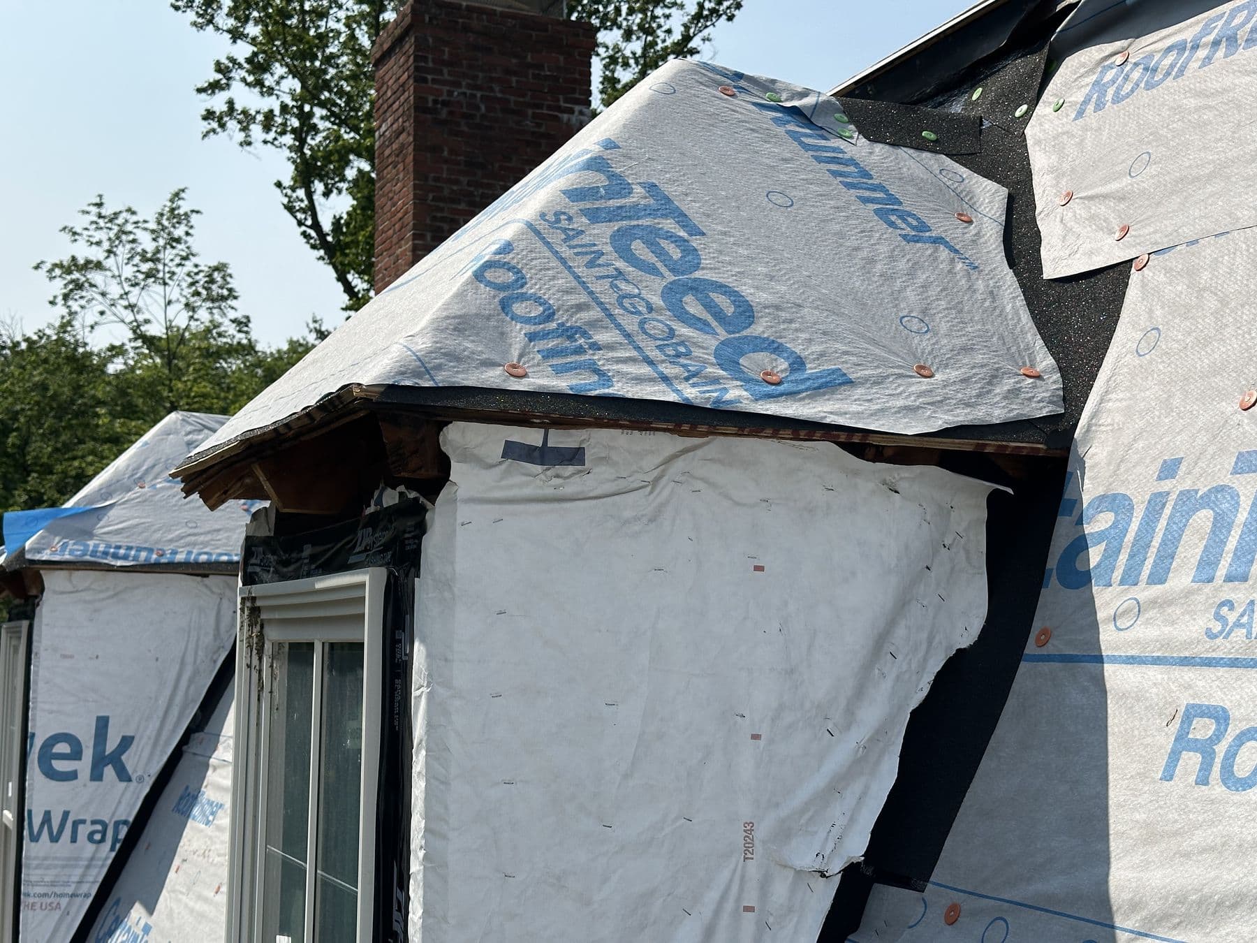 Two new dormers framed into the gambrel roof next to the chimney, wrapped and flashed