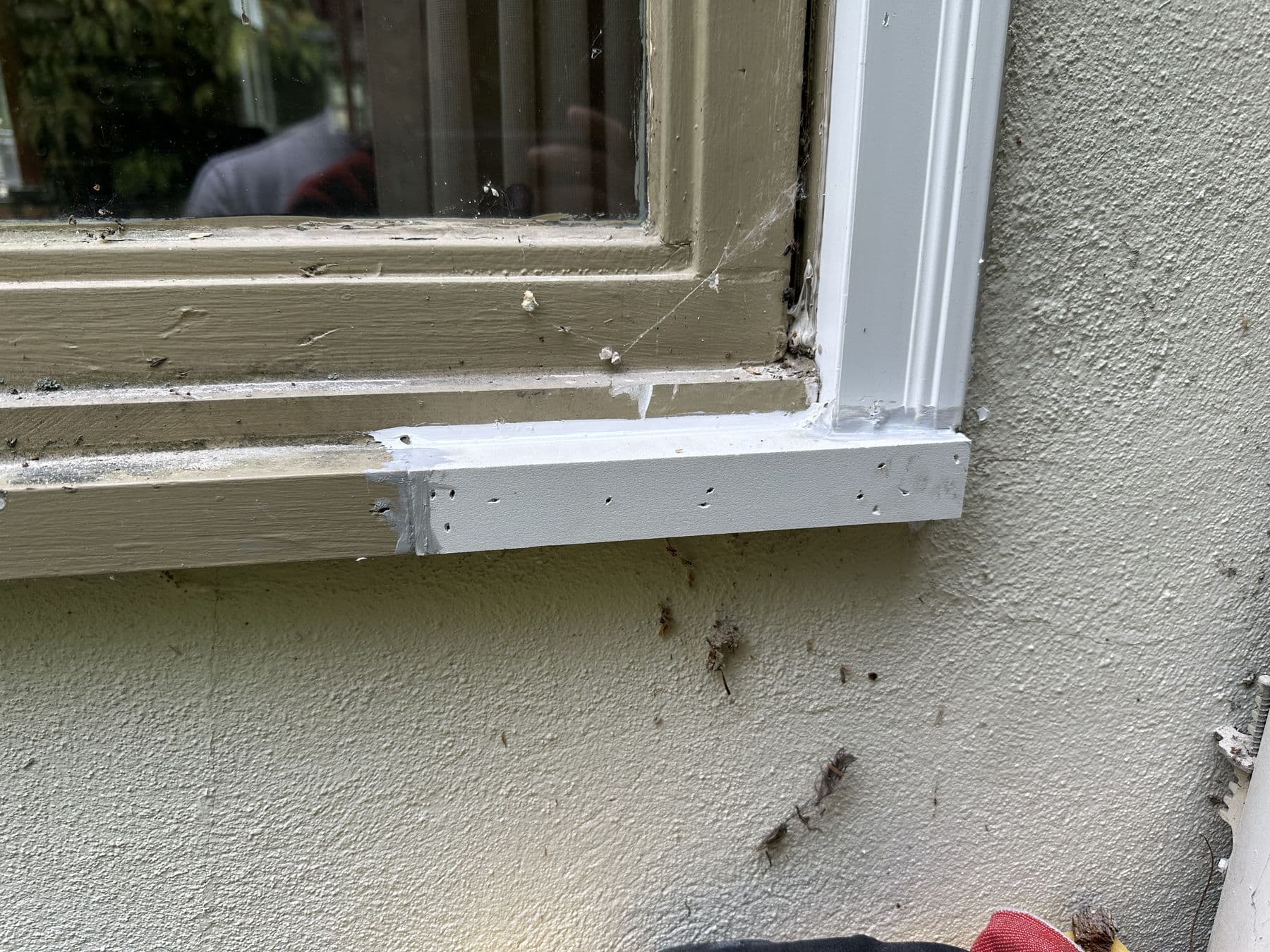 New PVC sill and trim fitted under the window on the stucco wall
