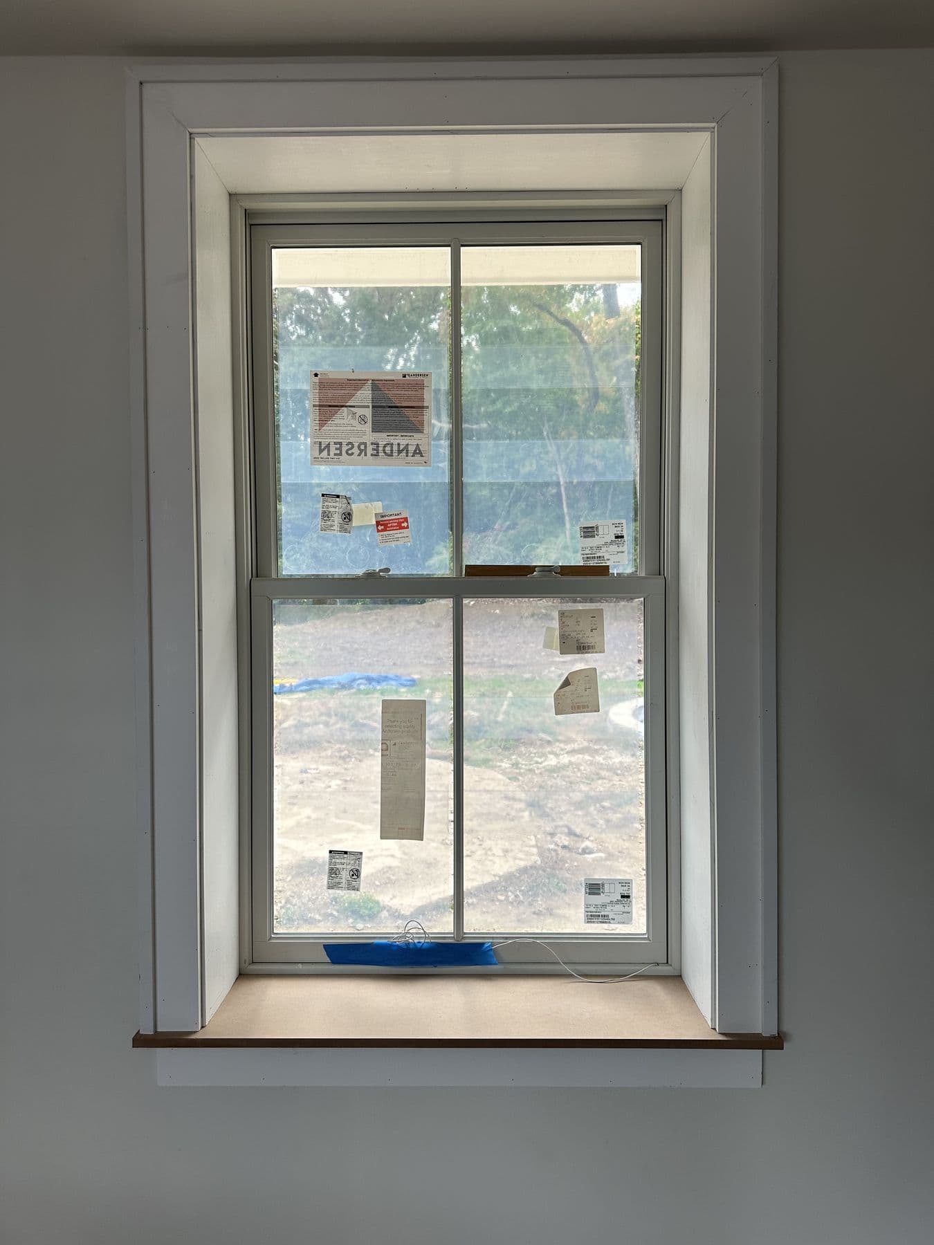 New double-hung window with white casing and stickers still on the glass