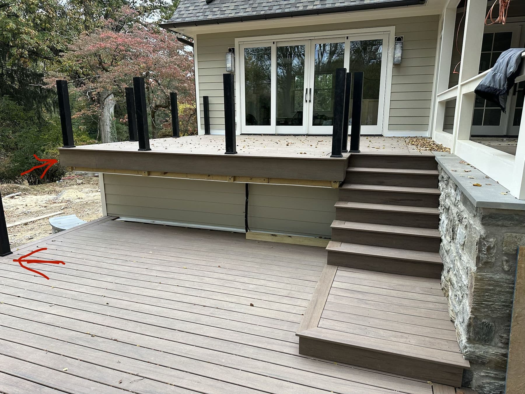Composite deck with glass railing posts, steps and a stone-clad base