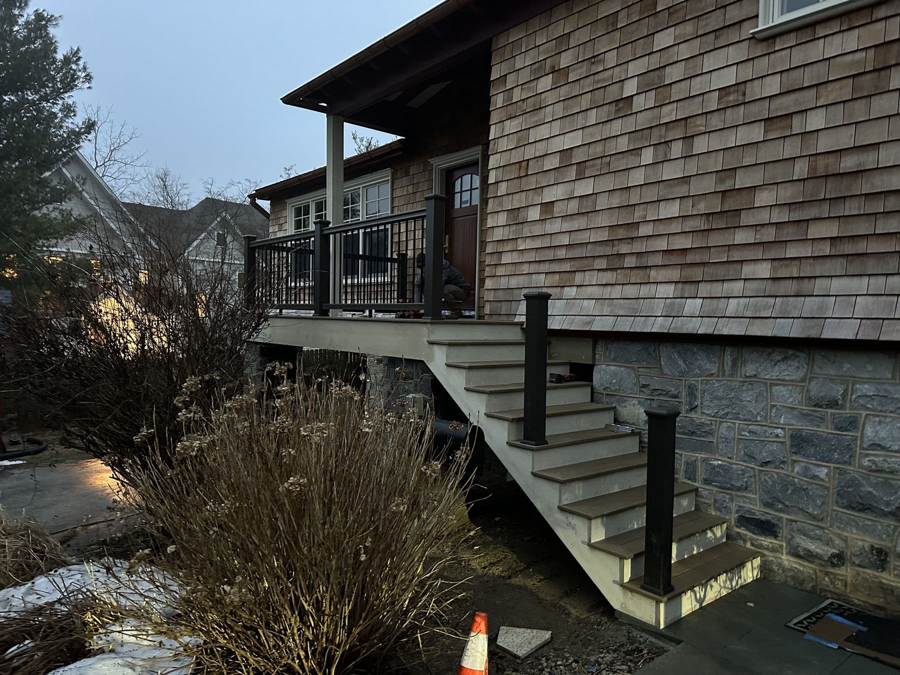 Deck stairs with black railing coming down the side of the cedar shake house