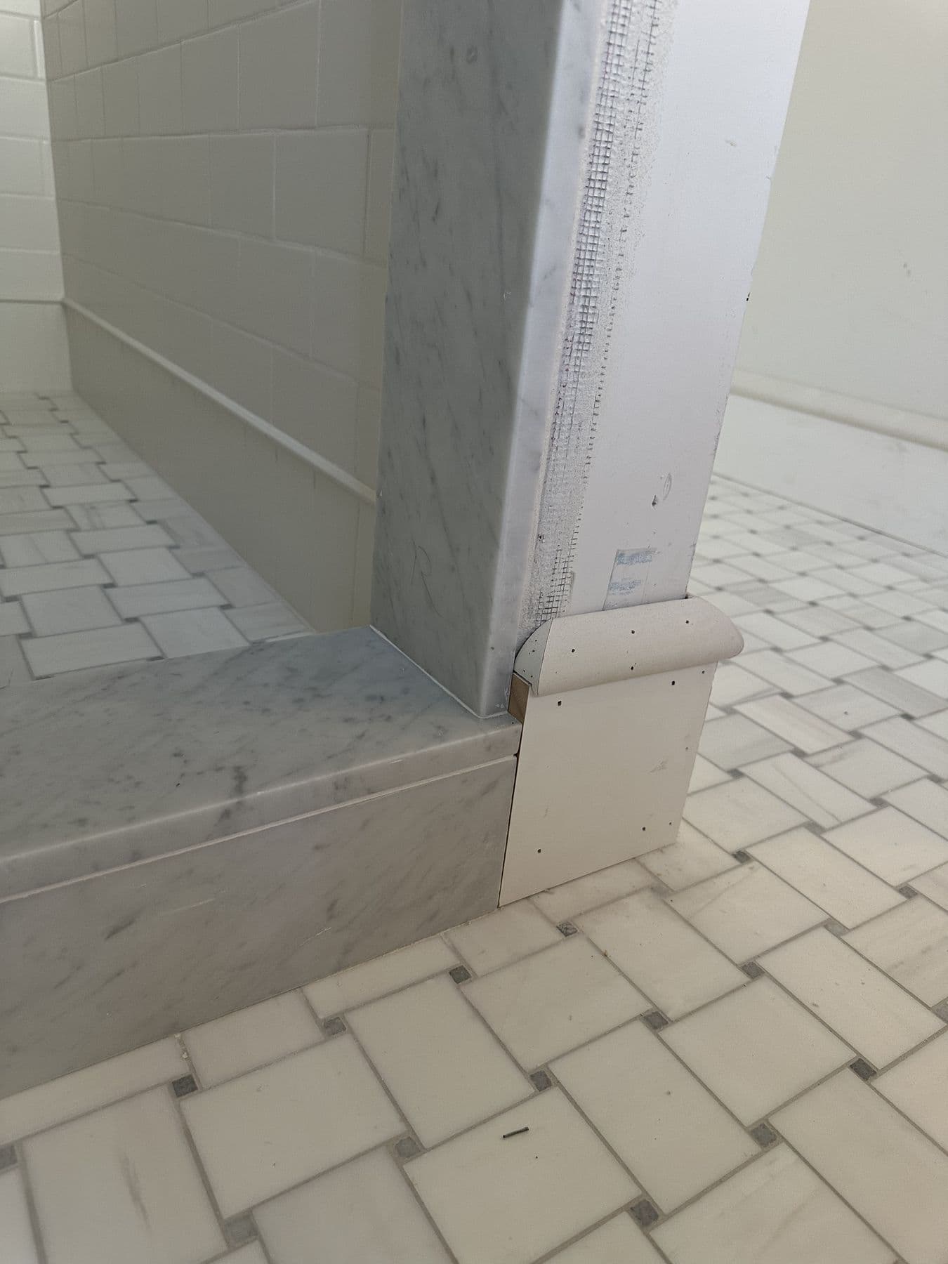 Built-out corner with panel trim in a tiled bathroom