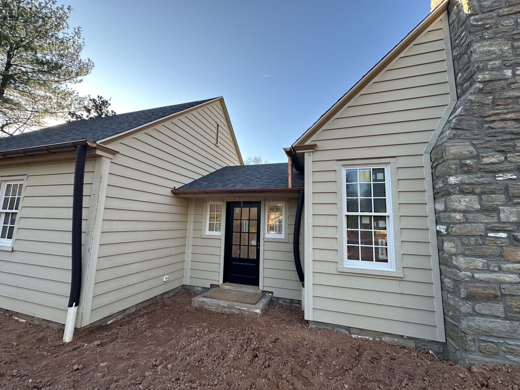 Rear of the building with a stone chimney, lap siding and a black door