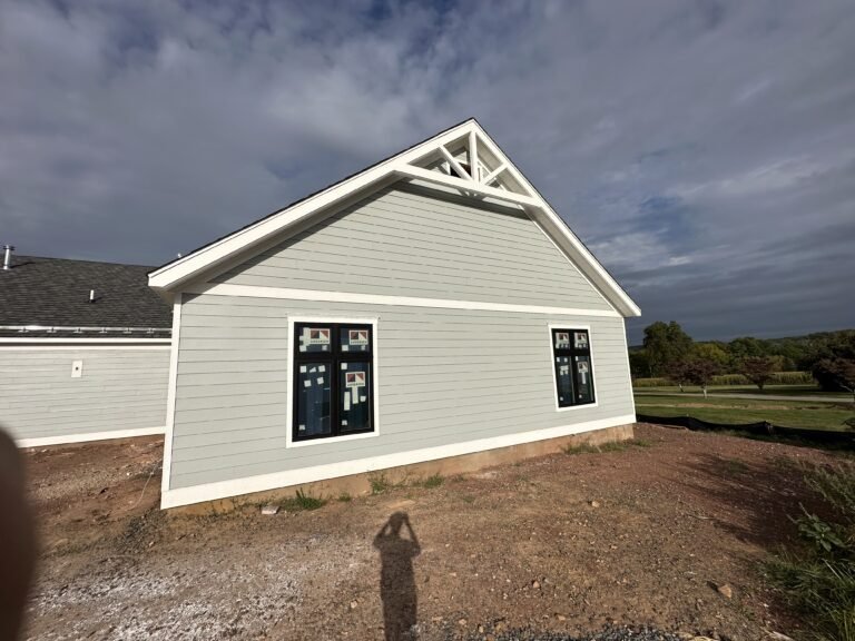 Sage gray lap siding gable with black windows and a decorative gable truss on a single-story home