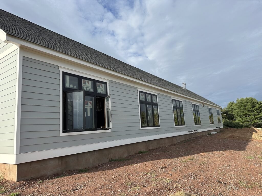 Long single-story home elevation with gray lap siding and black casement windows