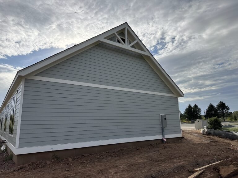 Light gray lap siding gable with white trim and a decorative gable truss on a single-story home