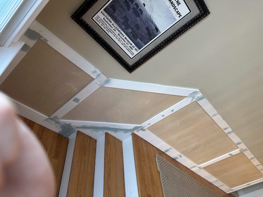 Paneled wainscoting under construction along a staircase wall with oak treads