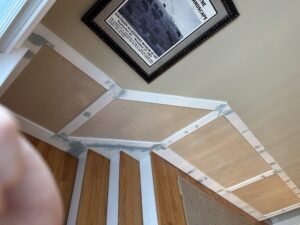 Paneled wainscoting under construction along a staircase wall with oak treads
