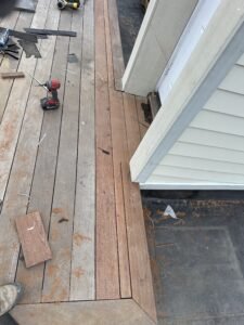 Composite deck boards being installed beside a sided wall during construction