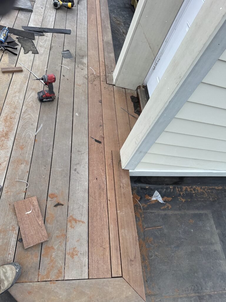 Composite deck boards being installed beside a sided wall during construction