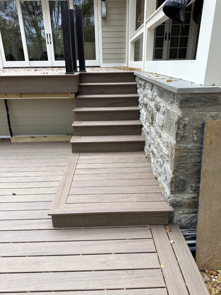 Composite deck stairs with pressure-treated framing and stone wall bluestone cap during deck construction in Lititz PA Lancaster County by D&E Mako Renovation