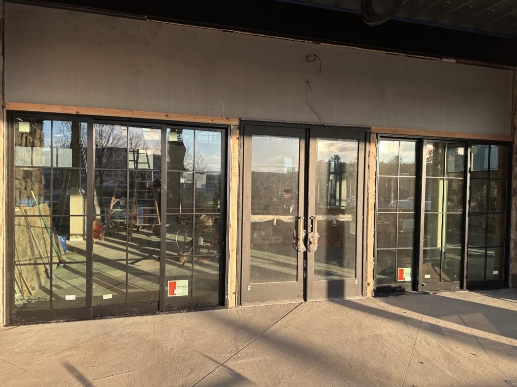 Black-framed commercial storefront glass windows and double doors newly installed on a building