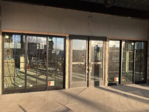 Black-framed commercial storefront glass windows and double doors newly installed on a building