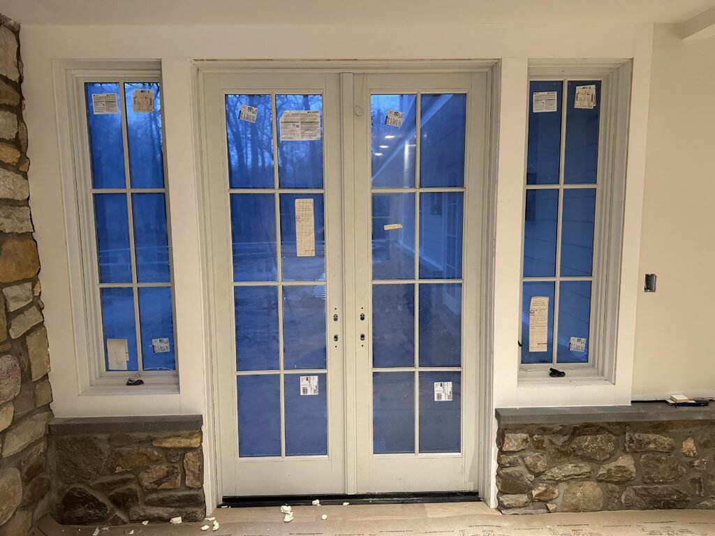 White French doors with sidelights and divided lites set into an interior stone wall at night