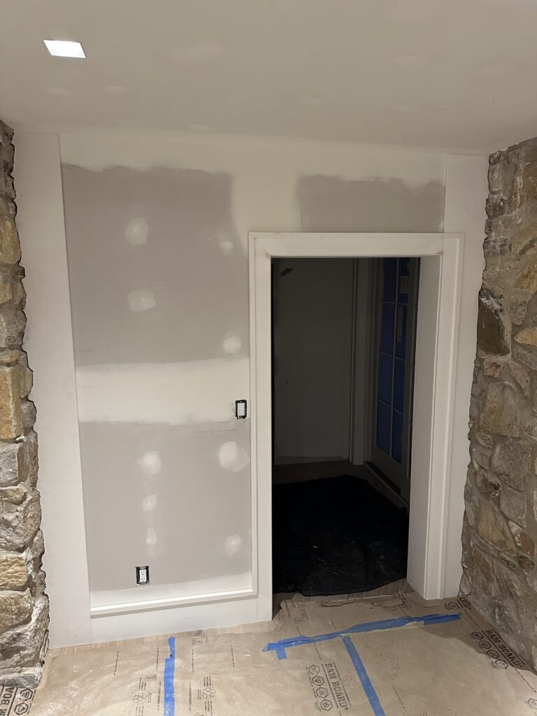 White-cased doorway between a drywalled wall and thick fieldstone interior walls during renovation