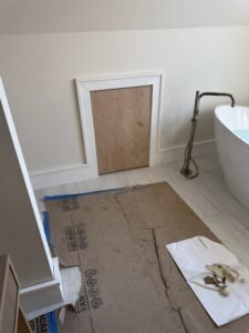 Freestanding soaking tub with a floor-mounted filler in a bathroom under a sloped ceiling during construction
