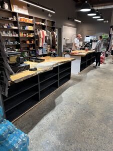 Custom live-edge wood checkout counters on black cabinetry in a retail store with polished concrete floor