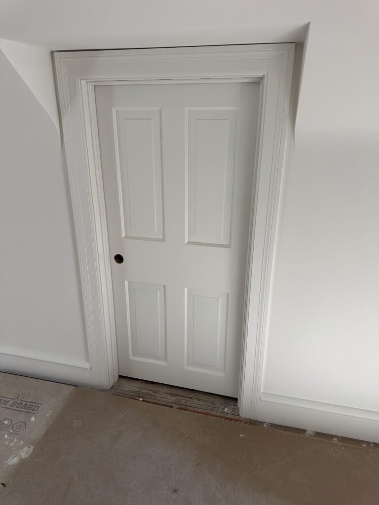  Interior renovation Downingtown PA hallway showing new white oak hardwood floors, chair rail trim, Marvin window, and mosaic bathroom tile floor visible through doorway