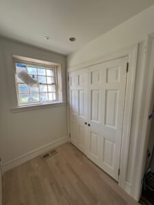 Finished bedroom with a white double-hung window, white closet doors, and refinished oak flooring