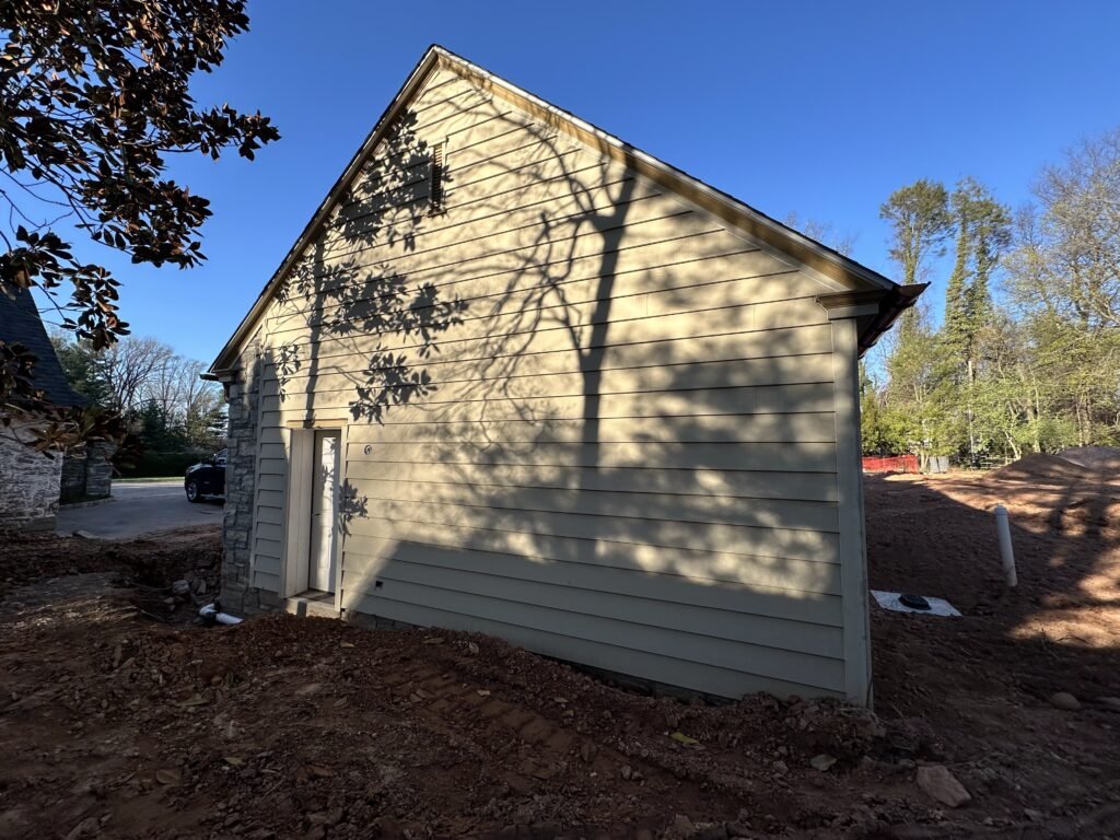 Cream clapboard siding with a stone foundation base on a home gable end after siding installation