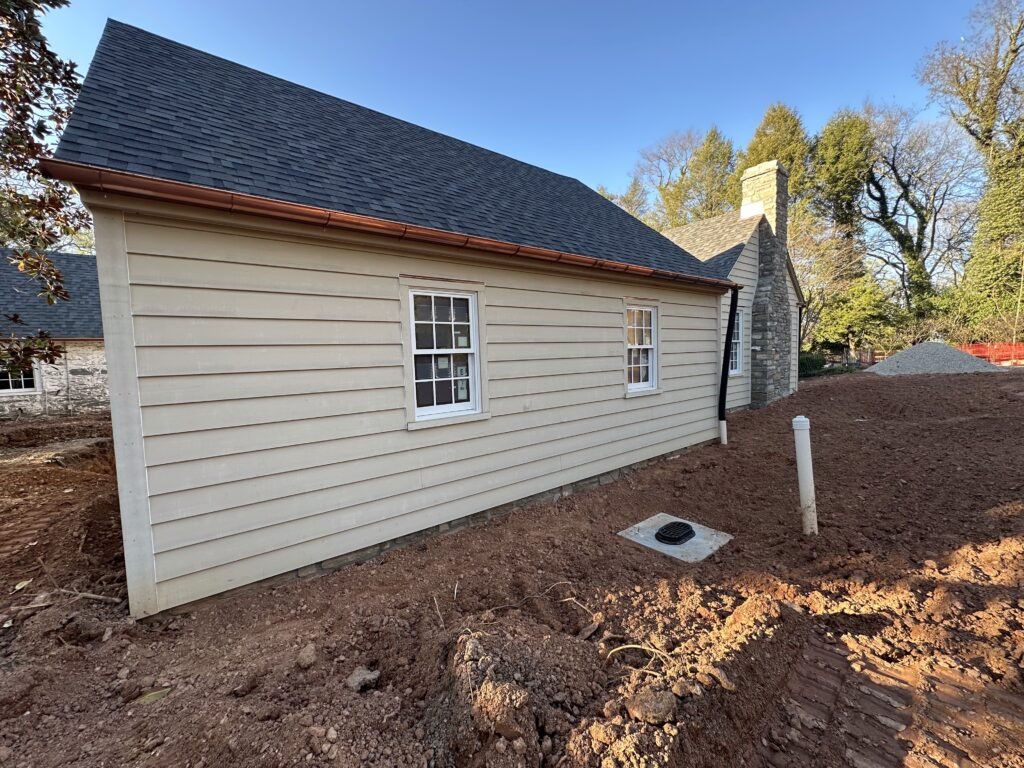 Newly installed cream fiber cement clapboard siding on a home with a dark shingle roof